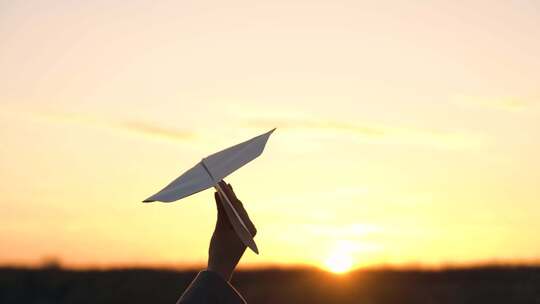 夕阳下纸飞机拿着纸飞机