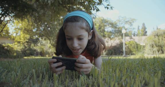 女孩独自趴在草坪上玩手机