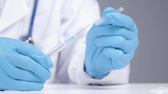 医学专业人员用注射器从小瓶中提取新冠肺炎疫苗