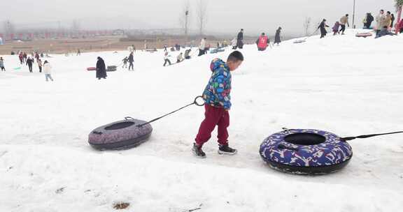 小男孩在雪地上拖着雪圈玩耍 滑雪场