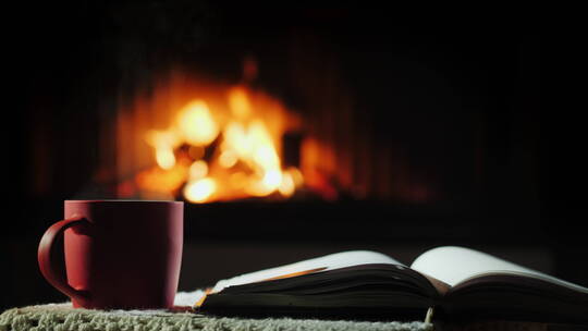 书和热茶在燃烧的壁炉背景上