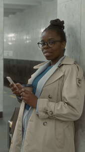 地铁里拿着电话和咖啡的积极黑人女士的垂直