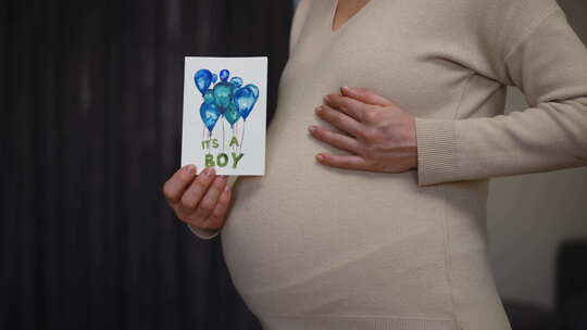 一名无法辨认的孕妇拿着未出生孩子的生日贺