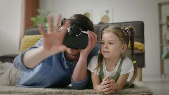 高兴的父亲在游戏时间帮助女儿使用虚拟现实