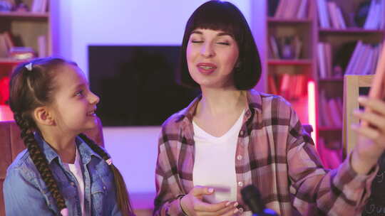 迷人的女人和小女孩使用手机视频流科学博客