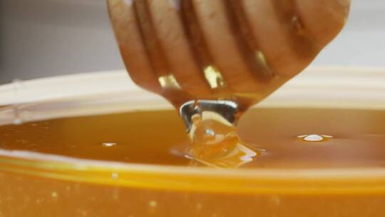 新鲜浓稠的液体相思蜂蜜从木制北斗星倾倒