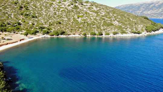 来自希腊阿吉亚索非亚海滩的伊萨卡海峡平静的蓝色水域。-空中平移视频素材模板下载