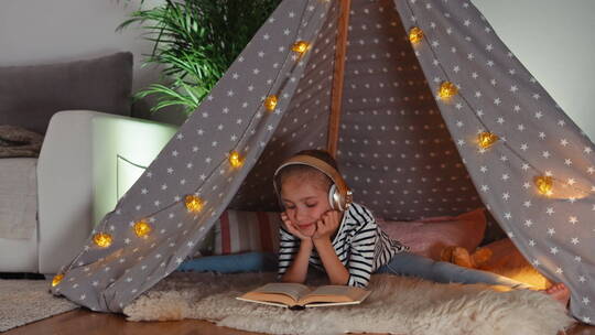 女孩在帐篷里戴着耳机看书视频素材模板下载
