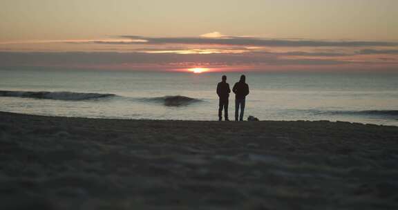 两个朋友站在沙滩上看日落