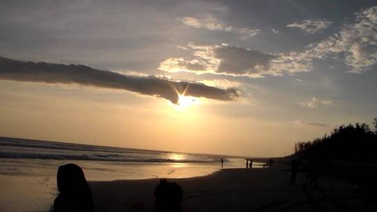 日落时海滩上人们身影