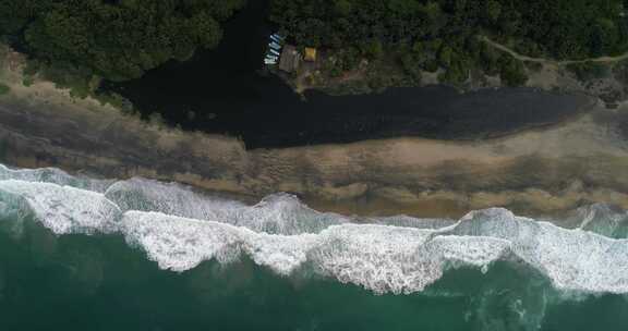 海滩天线上的小建筑和船只附近的波浪