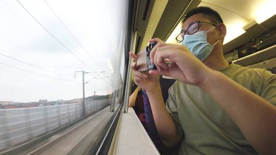 旅客在动车高铁上使用手机拍摄沿途风光