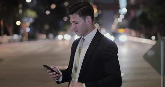 晚上站在路边看智能手机的商人