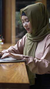 亚洲穆斯林妇女享受一个放松的时刻在的咖啡