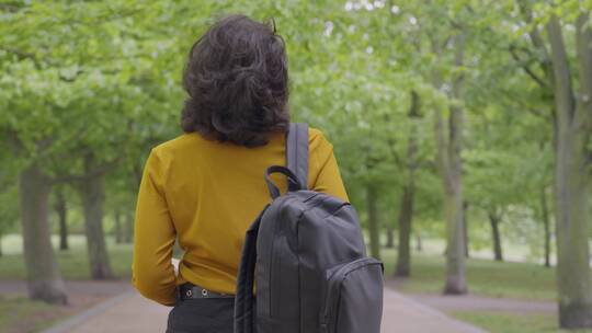 女人背着书包走在公园里延时