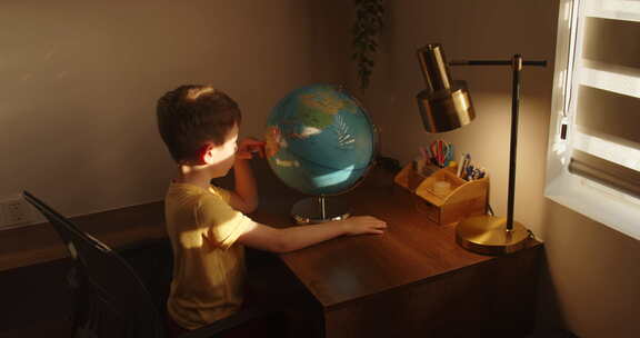 坐在家里的孩子学习在夕阳的光线下在房间里