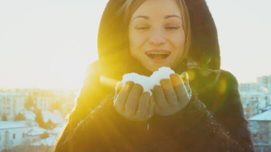 年轻女子在户外慢动作吹雪花