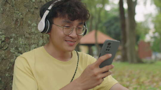 亚洲人在公园听电话音乐
