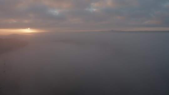 海面上的薄雾和云层，船只在黎明时分停泊在