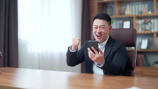 激动的亚洲商人手持智能手机喜出望外的商人