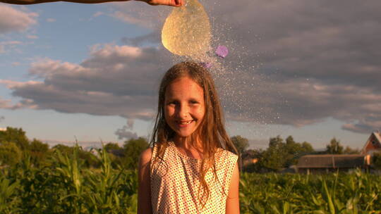 装满水的气球在小女孩头顶扎破