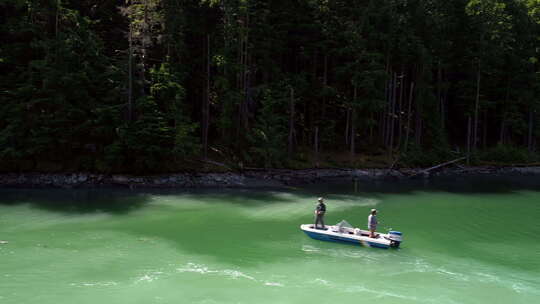 阳光明媚的一天，两个人在船上航行时在河里钓鱼