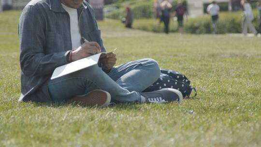 大学生坐在草地上学习