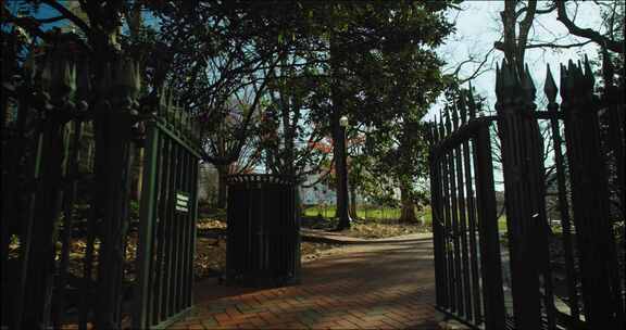公园树木和小径附近的金属栏杆和大门入口