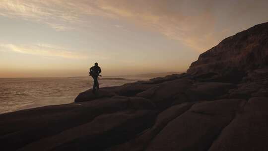 当海浪碰撞时，摄影师沿着海边的岩石行走