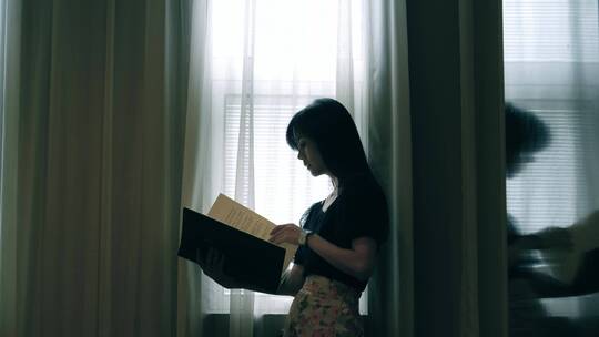 女孩在窗边看书的剪影视频素材