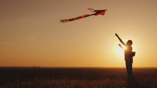 女人在夕阳下放风筝的剪影