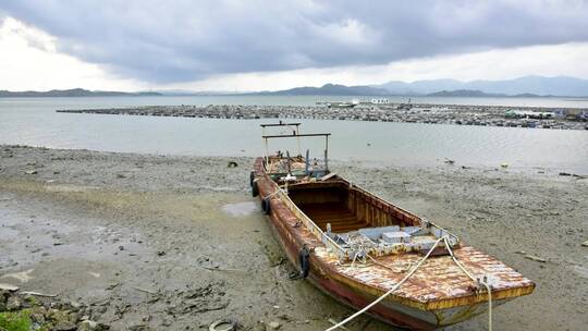 海边的晚霞滩涂和船只在行云落日下