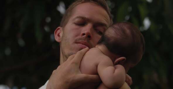 男人看着放在肩膀上的婴儿，轻轻地拍着背