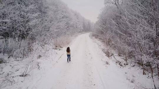 一名妇女在积雪的森林道路上奔跑