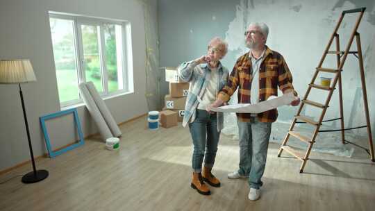 老人和女人正在浏览带有公寓平面图的床单并讨论装修