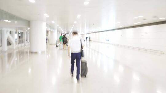 拖着行李箱行走在机场大厅内的男性乘客视频素材模板下载