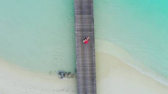 一名女子在海滩的码头上挥手