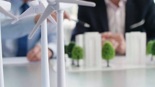 会议室介绍风力发电机和建筑模型的人士