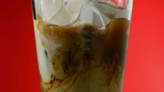 奶油掉进杯子里，红色背景是冰和咖啡