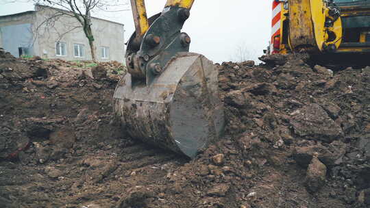 挖掘机臂舀起一桶土和石头
