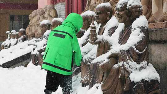 华顶寺雪天中的小男孩清理罗汉雕像积雪场景