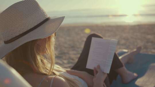 日落时在海滩上看书的女人