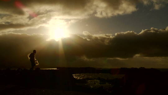 一个渔夫背着渔网走在日落前的精彩镜头
