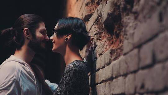 夫妇靠着砖墙亲吻