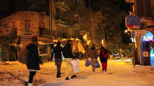 晚上人们走在积雪覆盖的道路上