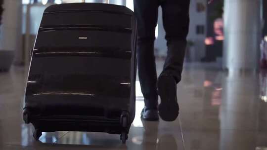 机场候机厅乘客拖着行李箱的特写