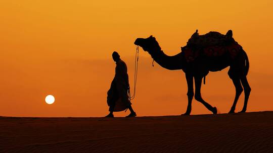 骆驼队在夕阳中穿越沙漠