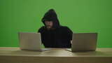 无法辨认的男子黑客穿着运动衫兜帽，在2台笔记本电脑上打字高清在线视频素材下载