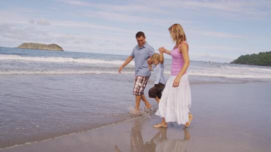 父母牵着孩子在沙滩漫步