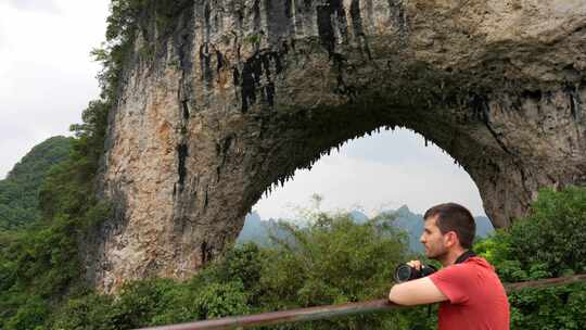 手持相机欣赏中国月亮山周围风景的游客。手